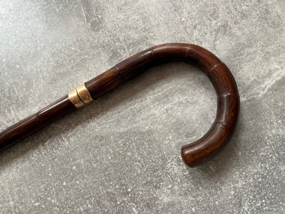 A dark wood walking stick featuring a crook handle and faux bamboo carved nodes, unsheathed to reveal a long steel blade alongside its wooden casing. View XIII