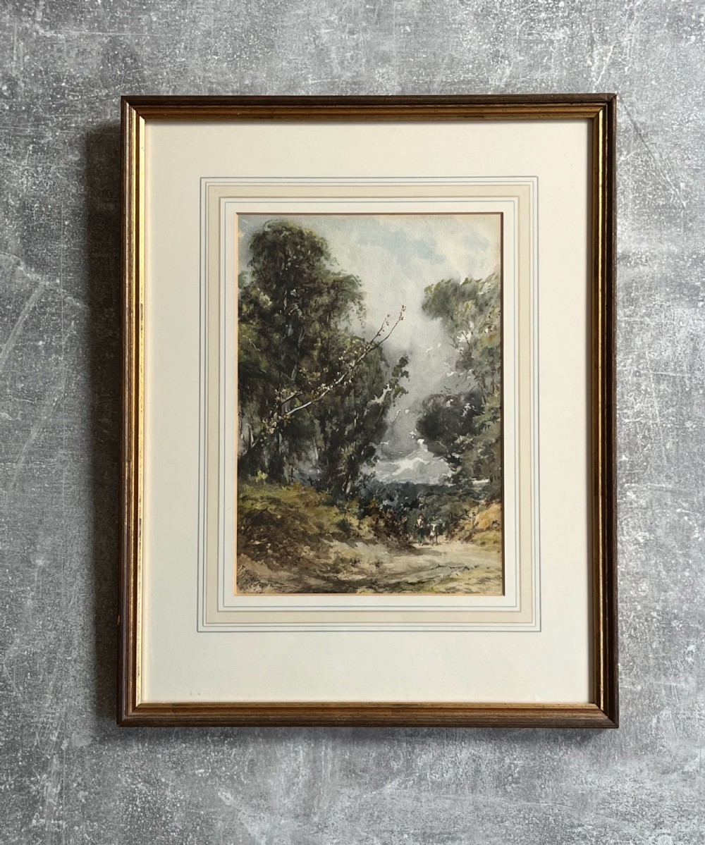 A framed 19th-century watercolour painting depicting a wooded countryside path under a clouded sky, mounted in a lined cream mat and narrow gilt-trimmed wooden frame. View VIII