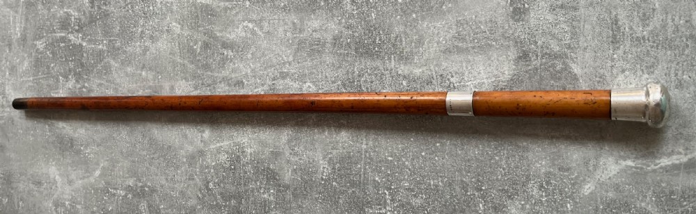 An antique malacca cane sword stick featuring a hallmarked silver pommel collar and an etched steel blade alongside its wooden sheath. View XVII