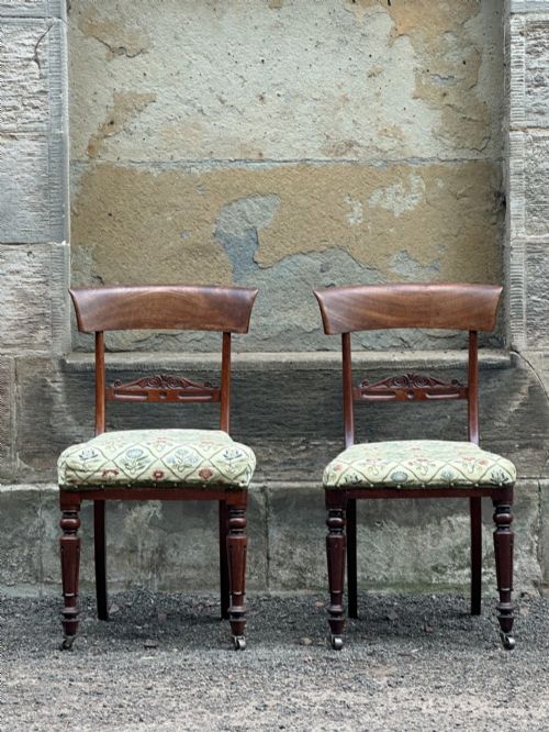 fig 1. A pair of Scottish Regency mahogany side chairs with curved top rails, carved back splats, upholstered seats, and turned front legs on castors.