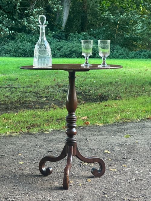 fig 1. A George III mahogany tripod table featuring a circular top supported by a turned central stem and three scrolled legs.