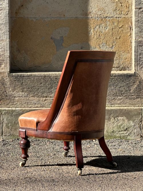 fig 2. A pair of nineteenth-century Greek Revival mahogany armchairs upholstered in warm brown leather with turned front legs on castors and incised geometric detailing.