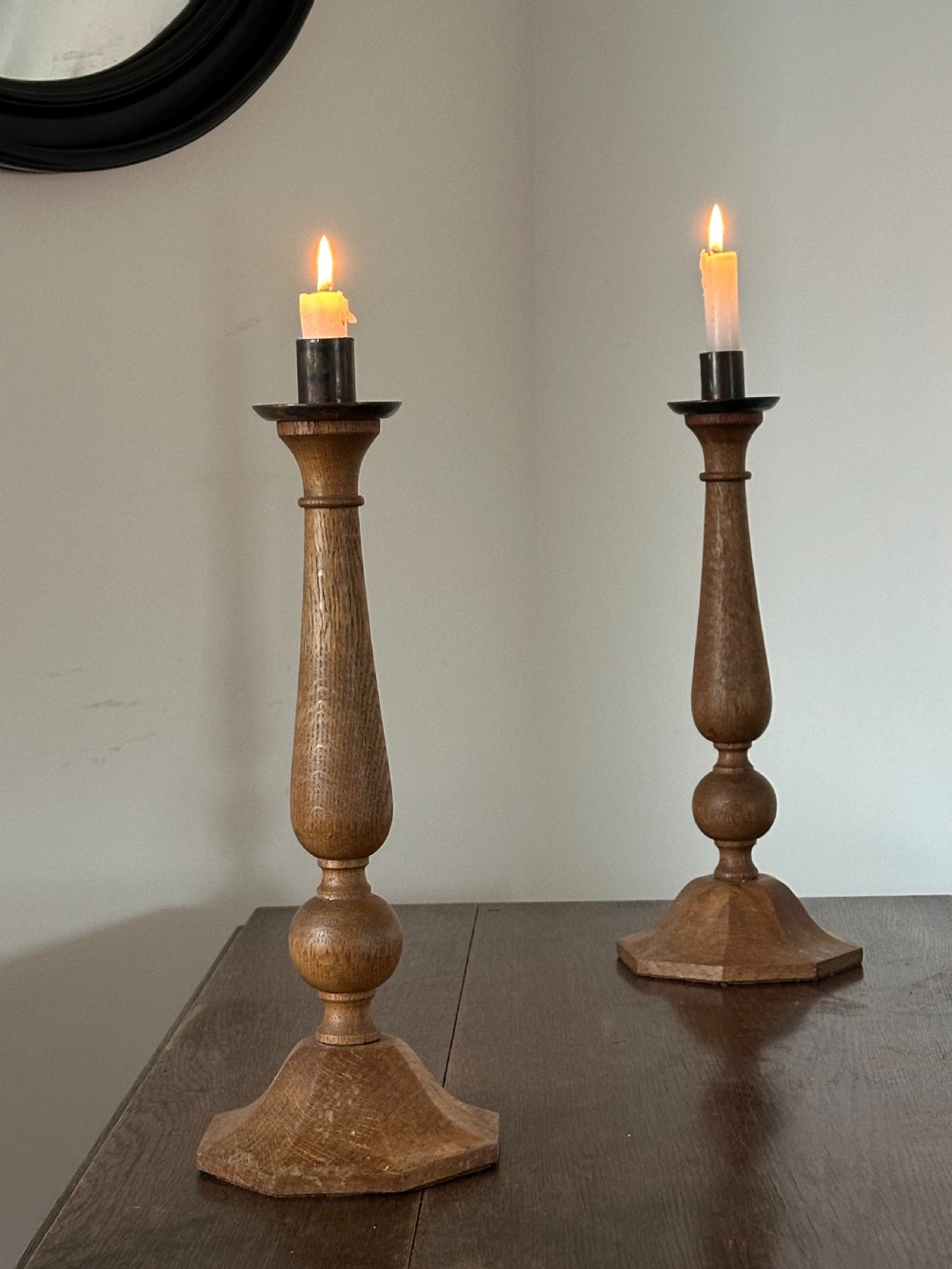 A pair of Arts and Crafts carved and turned oak candlesticks in the style of Sir Edwin Lutyens