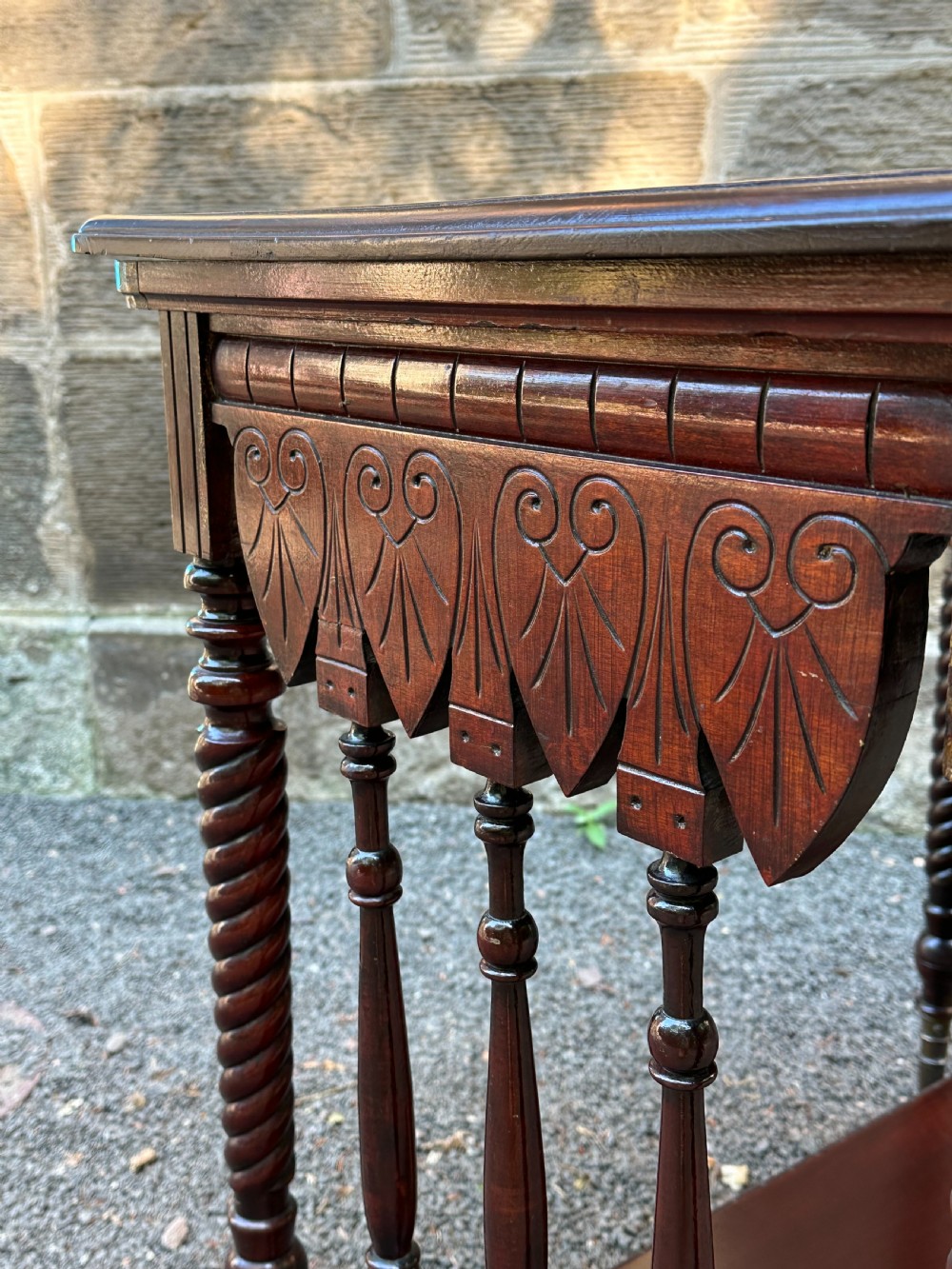 An Aesthetic Movement stained birch centre table featuring barley twist legs, carved foliage aprons, a lower tier with slender spindles, and brass sabots. View III