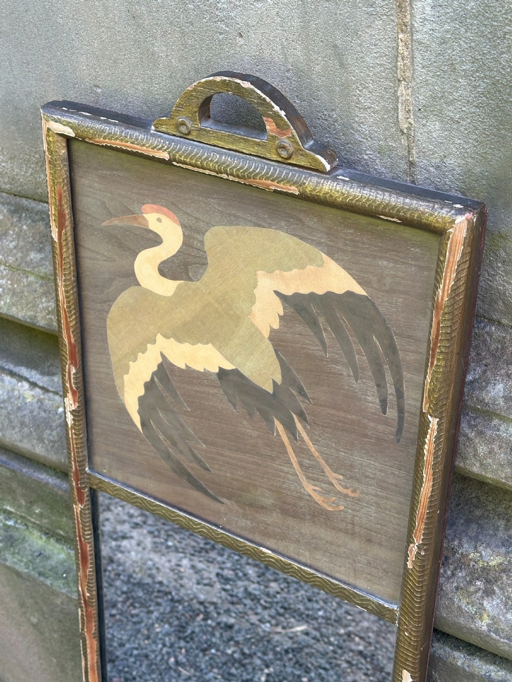 A tall rectangular Art Deco wall mirror featuring an upper wood marquetry panel depicting a crane in flight above a mirror glass section, encased in a silver-gilt frame. View III