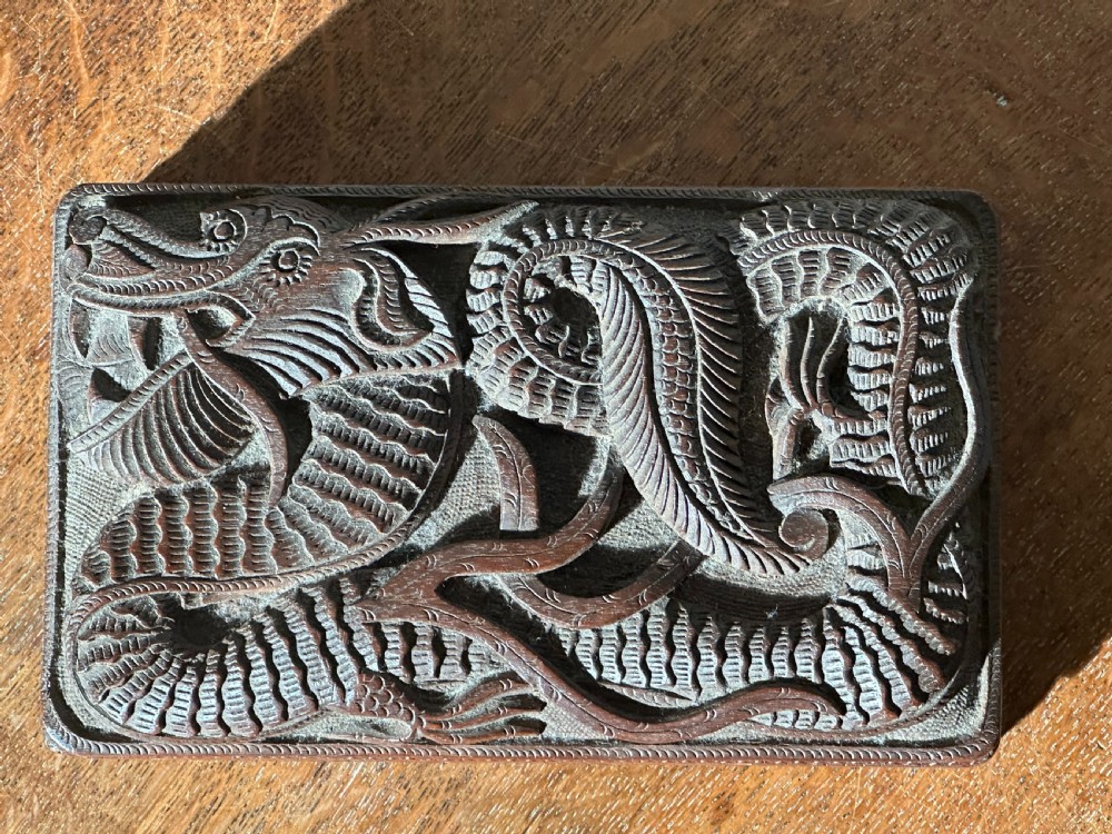 An overhead view of a rectangular, dark walnut box featuring intricate hand-carved relief decoration of a coiling dragon across the lid.