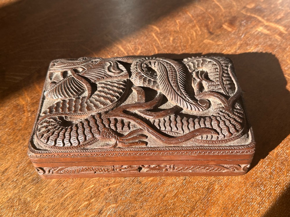 An overhead view of a rectangular, dark walnut box featuring intricate hand-carved relief decoration of a coiling dragon across the lid. View II
