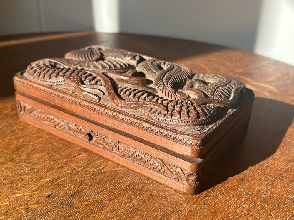 An overhead view of a rectangular, dark walnut box featuring intricate hand-carved relief decoration of a coiling dragon across the lid. View III