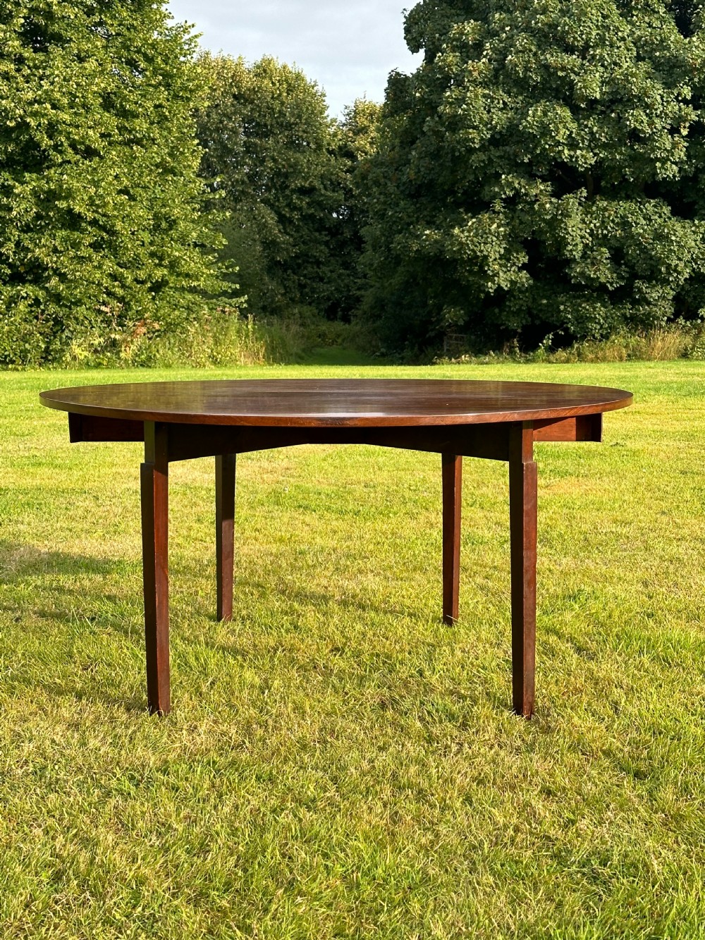A late 18th-century George III mahogany hunt table featuring two large semi-circular drop leaves and tapered square legs. View II