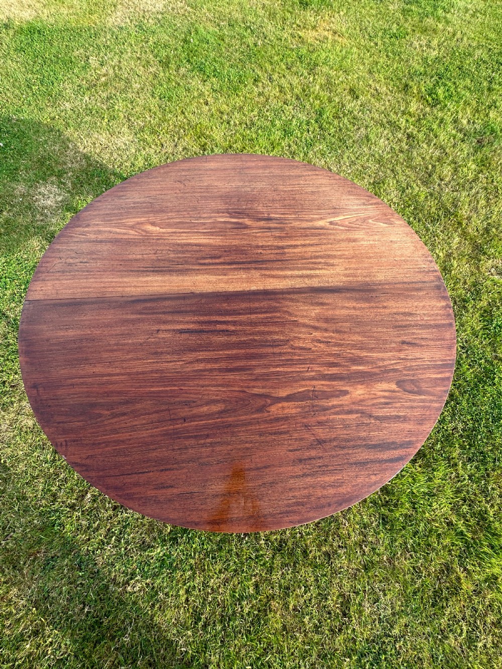 A late 18th-century George III mahogany hunt table featuring two large semi-circular drop leaves and tapered square legs. View III