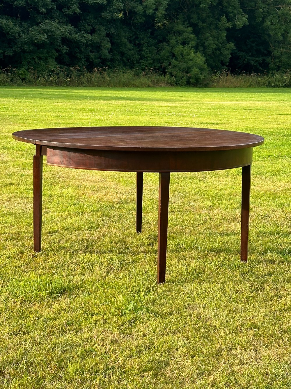 A late 18th-century George III mahogany hunt table featuring two large semi-circular drop leaves and tapered square legs. View IV