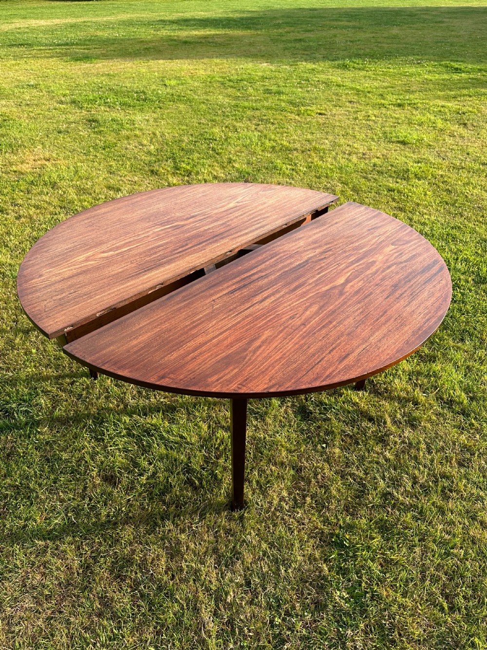 A late 18th-century George III mahogany hunt table featuring two large semi-circular drop leaves and tapered square legs.