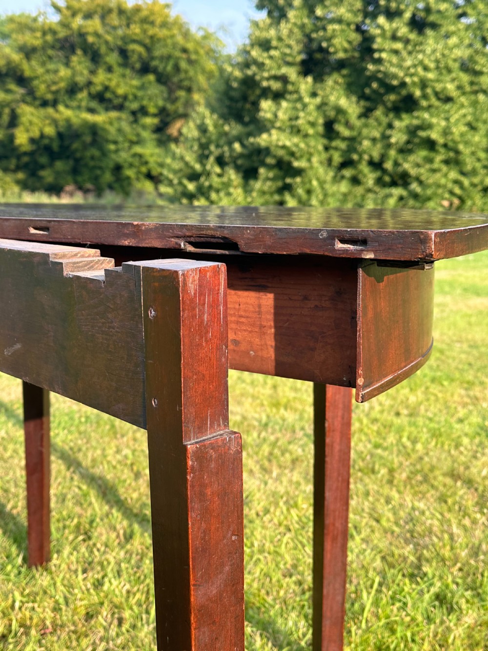 A late 18th-century George III mahogany hunt table featuring two large semi-circular drop leaves and tapered square legs. View XI
