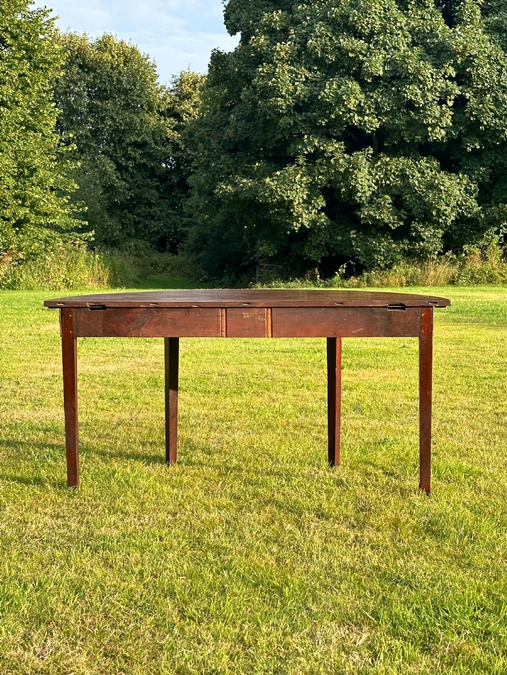A late 18th-century George III mahogany hunt table featuring two large semi-circular drop leaves and tapered square legs. View XII