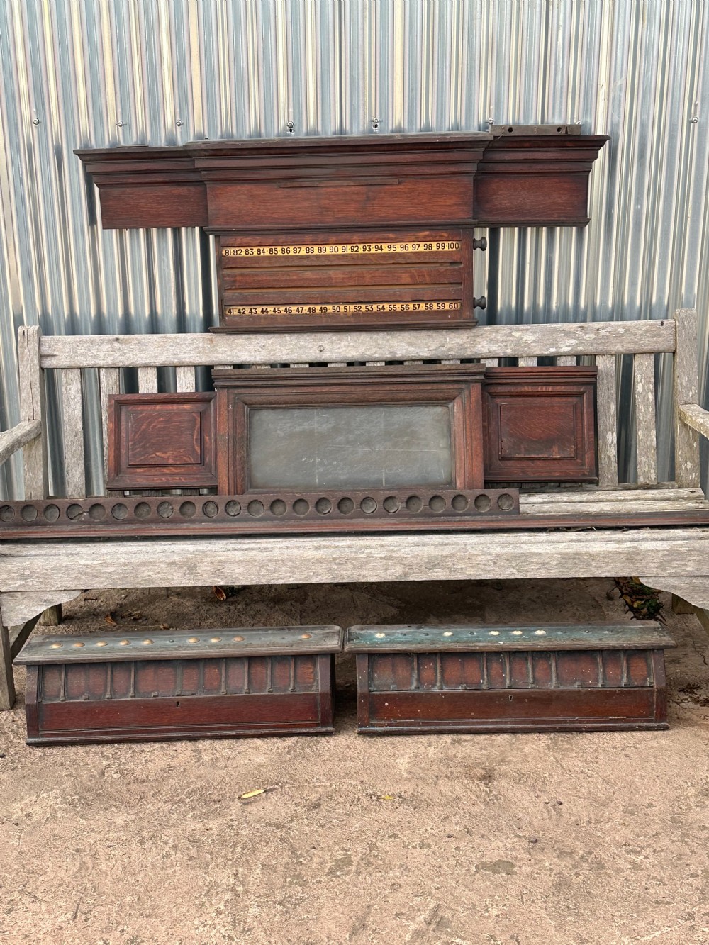 A nineteenth-century dark oak billiard scoreboard featuring numbered sliding brass pointers, moulded architectural cornices, and lower storage compartments.