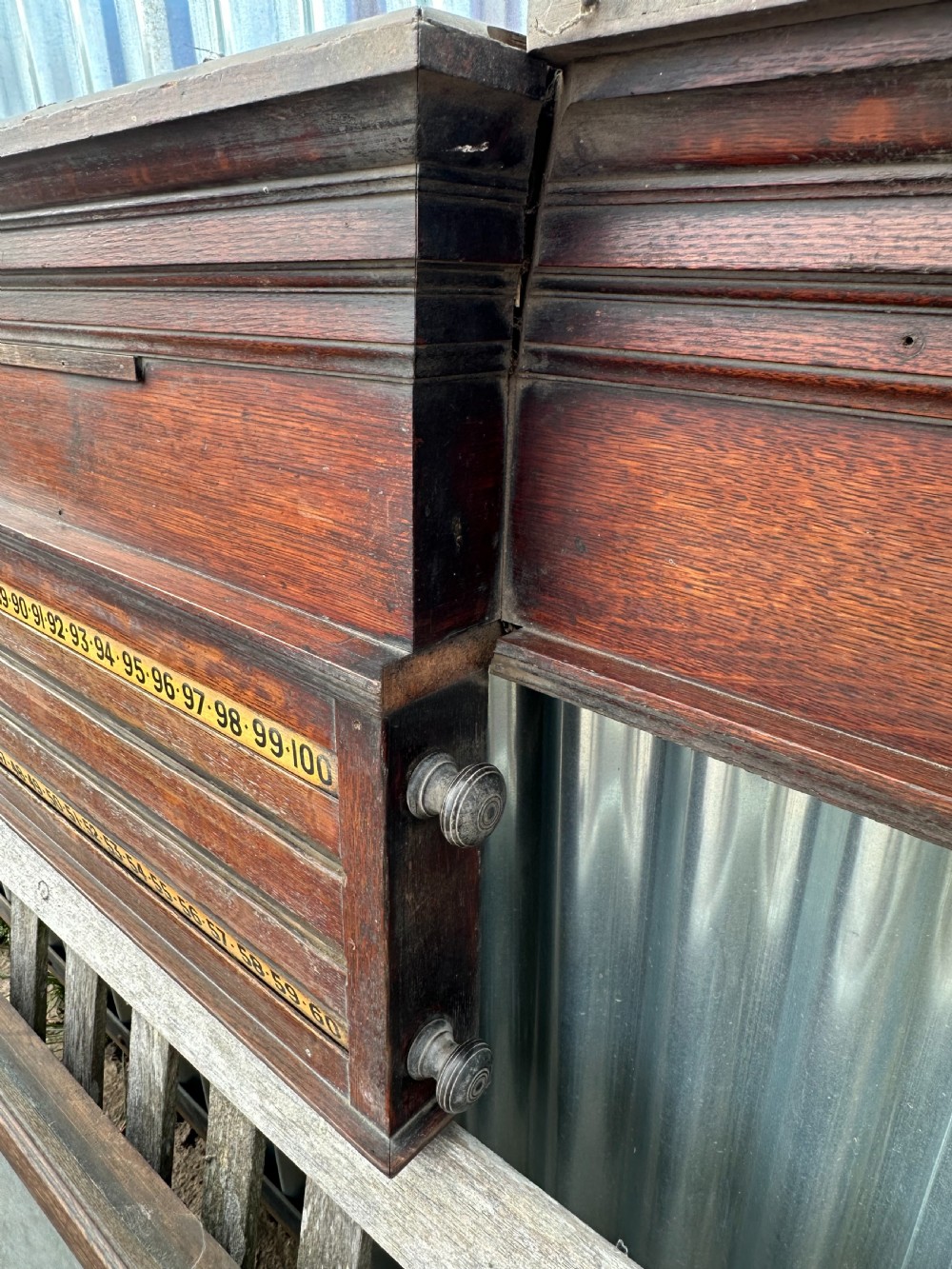 A nineteenth-century dark oak billiard scoreboard featuring numbered sliding brass pointers, moulded architectural cornices, and lower storage compartments. View V