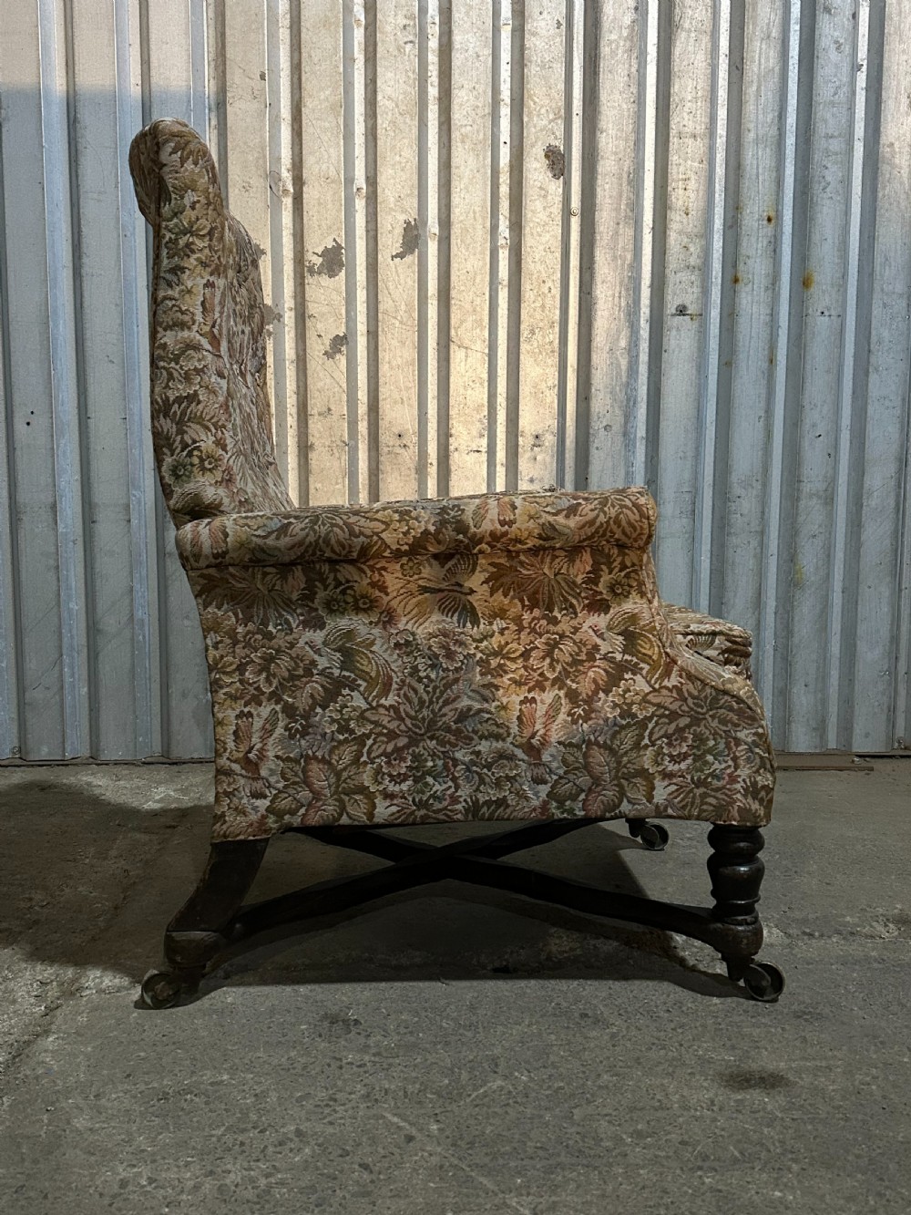 A mid-19th-century English ebonised reclining library armchair with patterned fabric upholstery and turned front legs on brass castors. View IV