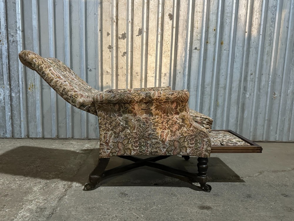 A mid-19th-century English ebonised reclining library armchair with patterned fabric upholstery and turned front legs on brass castors. View V