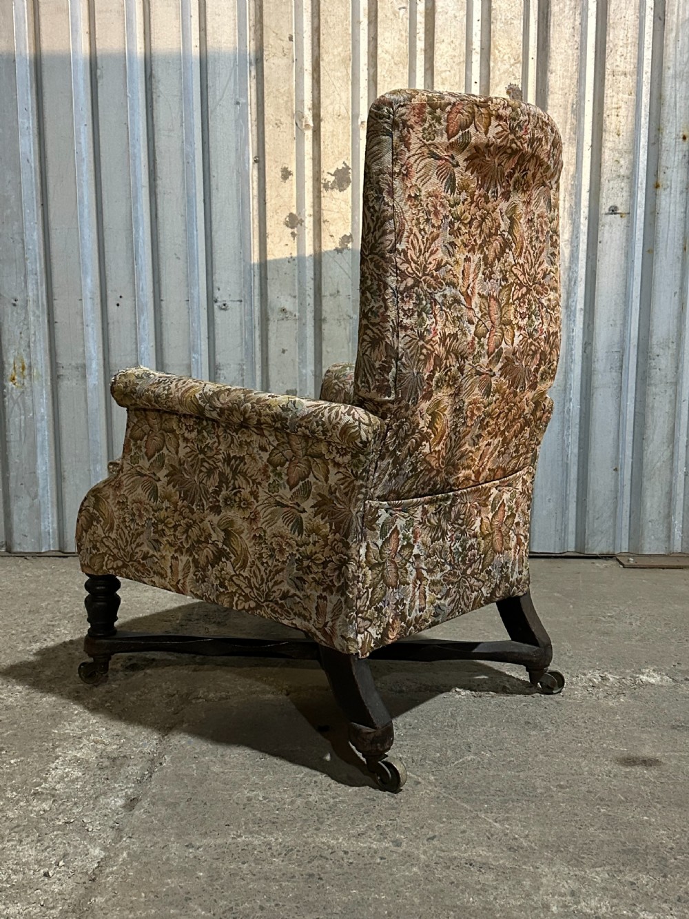 A mid-19th-century English ebonised reclining library armchair with patterned fabric upholstery and turned front legs on brass castors. View VI