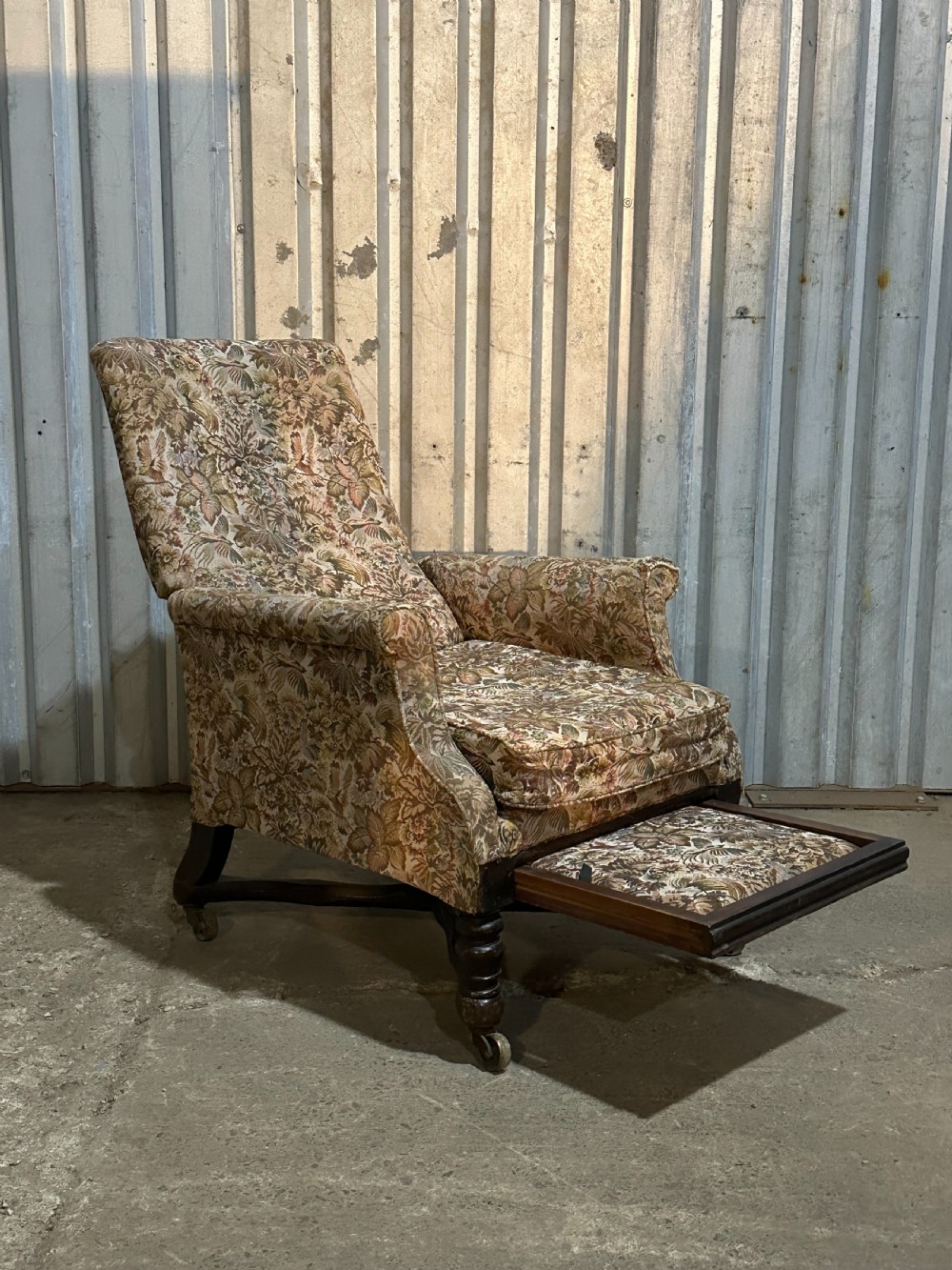 A mid-19th-century English ebonised reclining library armchair with patterned fabric upholstery and turned front legs on brass castors. View VII