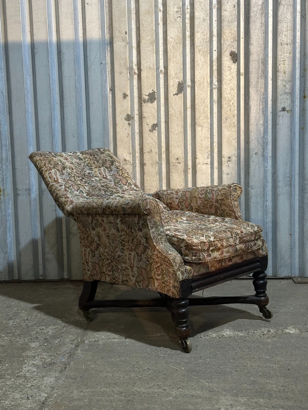 A mid-19th-century English ebonised reclining library armchair with patterned fabric upholstery and turned front legs on brass castors. View X