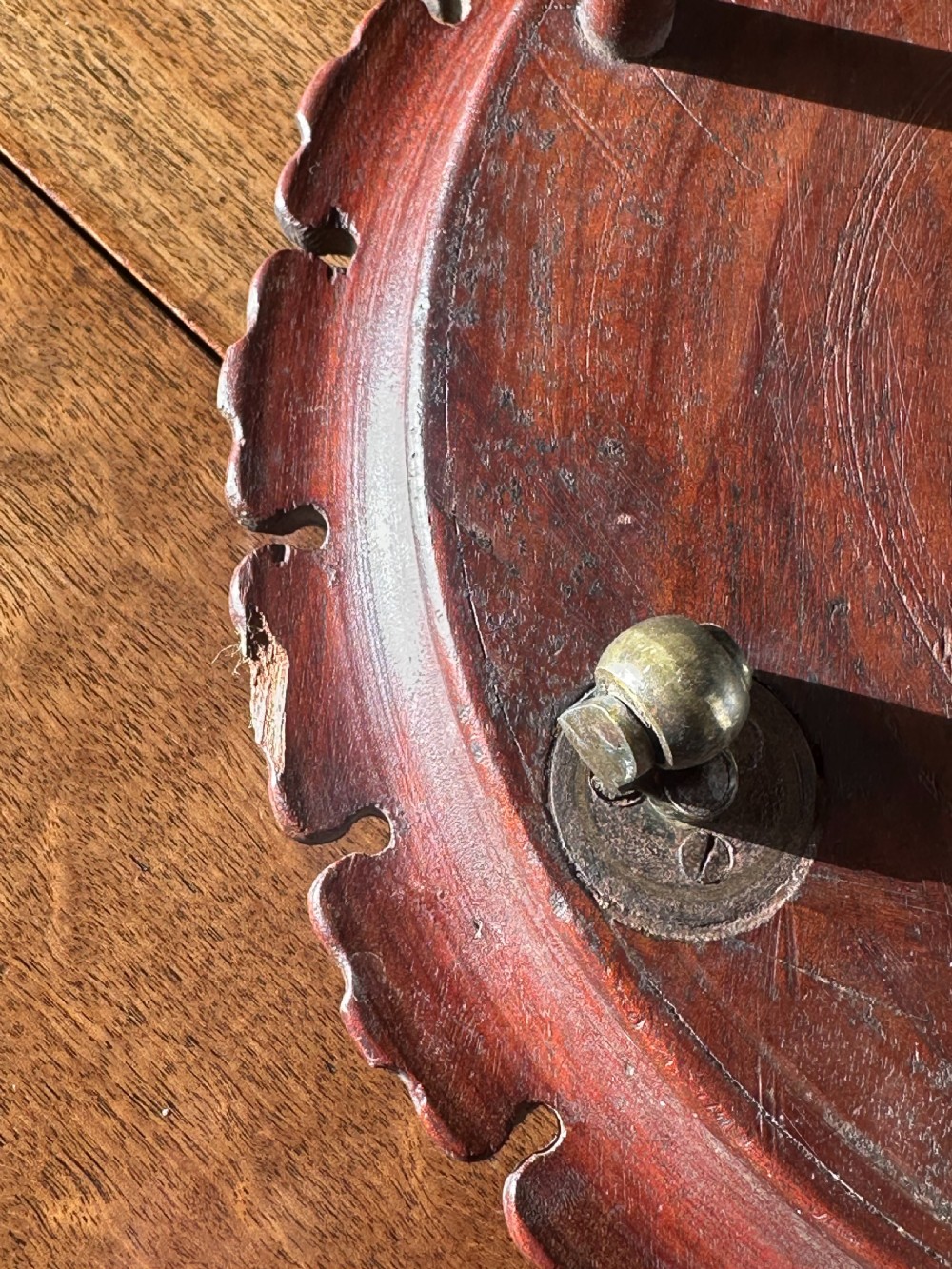 A circular carved mahogany decanter coaster featuring intricate central geometric patterns, a gadrooned rim, and small castors mounted underneath. View IV