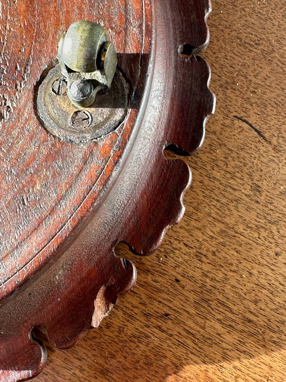 A circular carved mahogany decanter coaster featuring intricate central geometric patterns, a gadrooned rim, and small castors mounted underneath. View VI