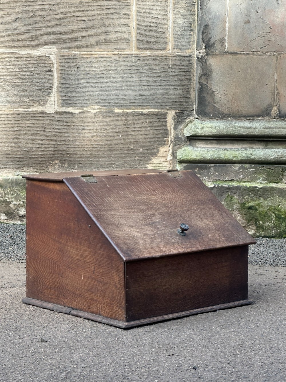 A Scottish George III period oak coal bunker featuring a slanted hinged lid with a dark turned wooden knob and brass strap hinges.