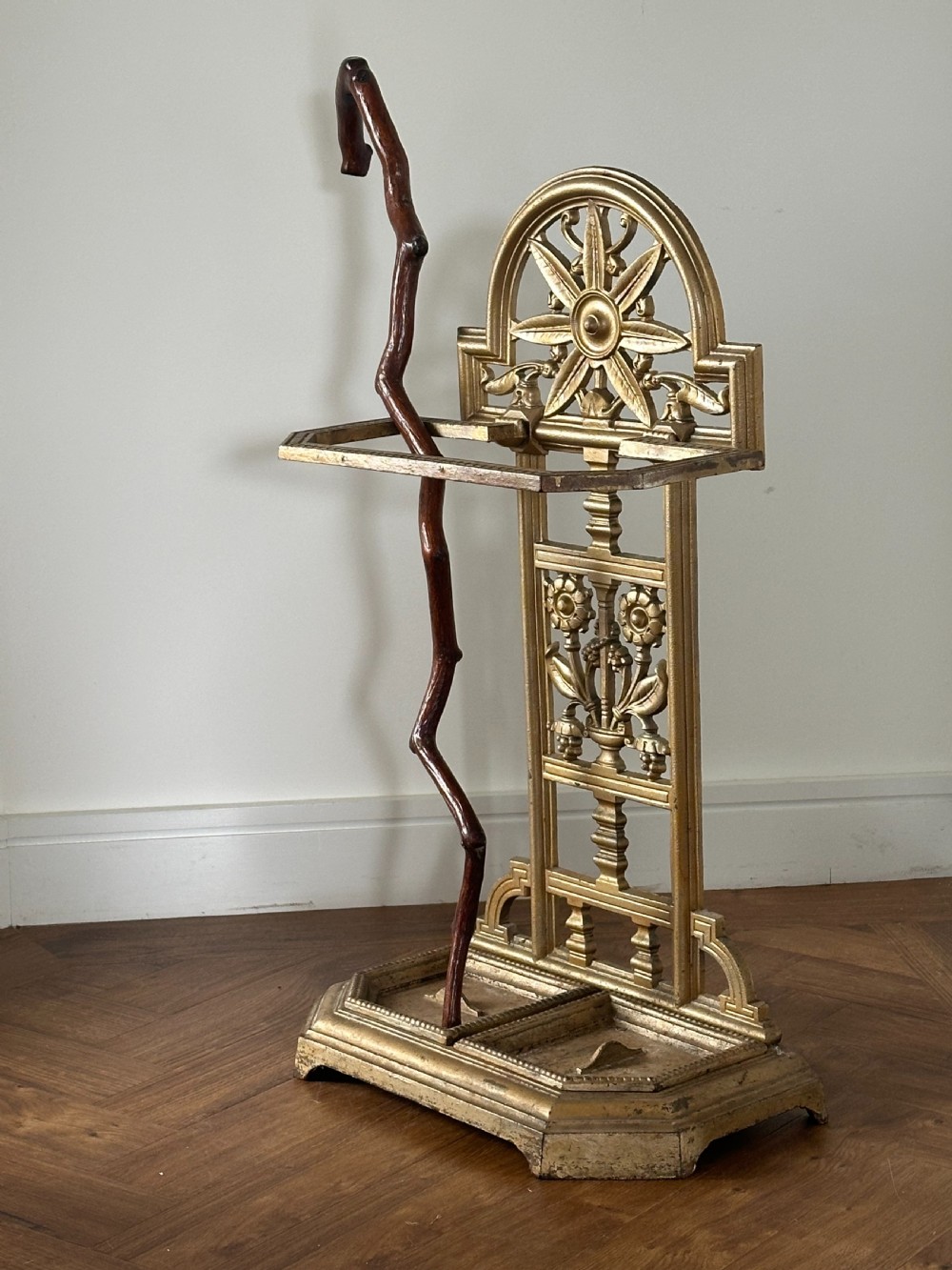 A gold-painted cast iron stick stand featuring a starburst arched cresting, stylised floral central panel, rectangular top ring, and a heavy drip tray base. View III