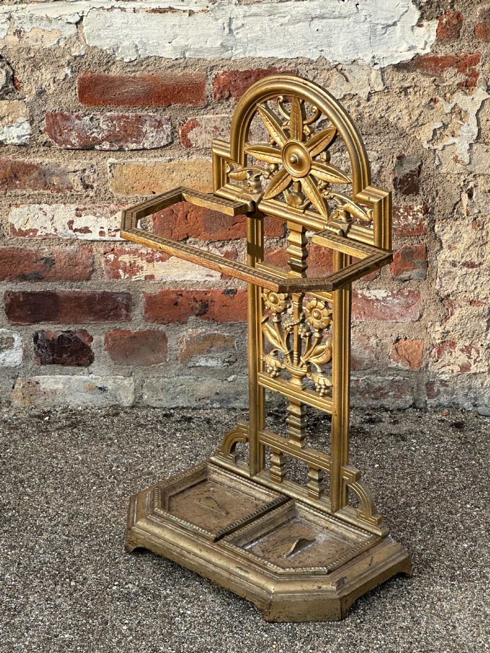 A gold-painted cast iron stick stand featuring a starburst arched cresting, stylised floral central panel, rectangular top ring, and a heavy drip tray base. View VI