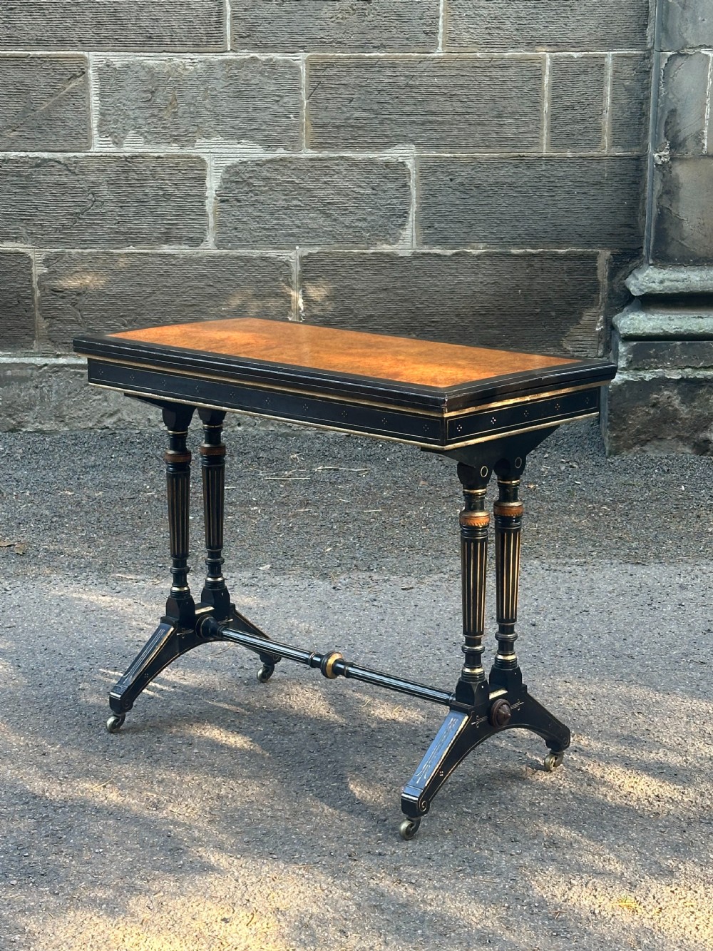 A late Victorian ebonised and parcel gilt card table with a green baize top and turned amboyna columns. View II