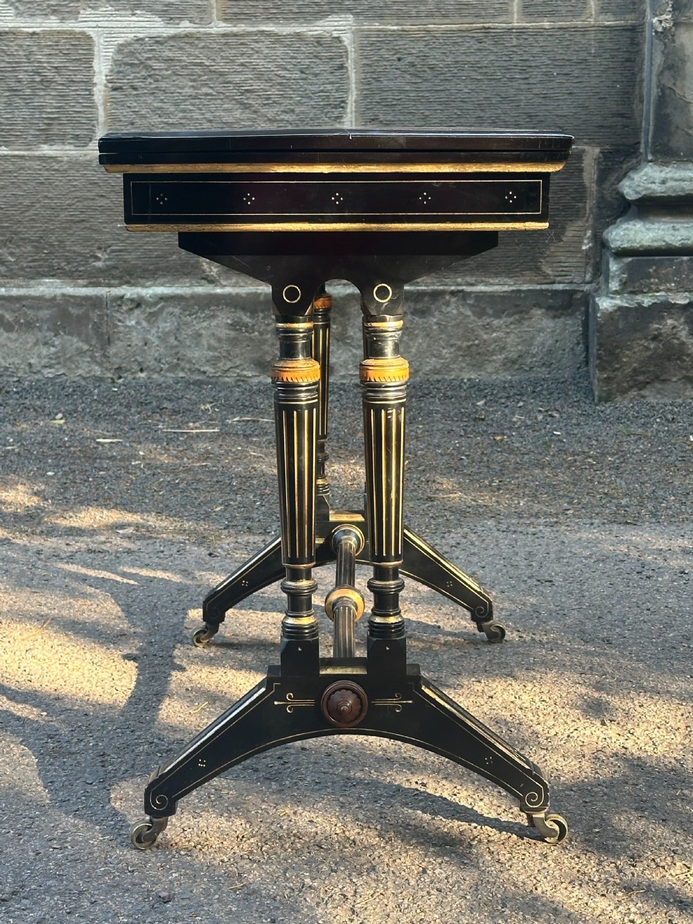 A late Victorian ebonised and parcel gilt card table with a green baize top and turned amboyna columns. View VI