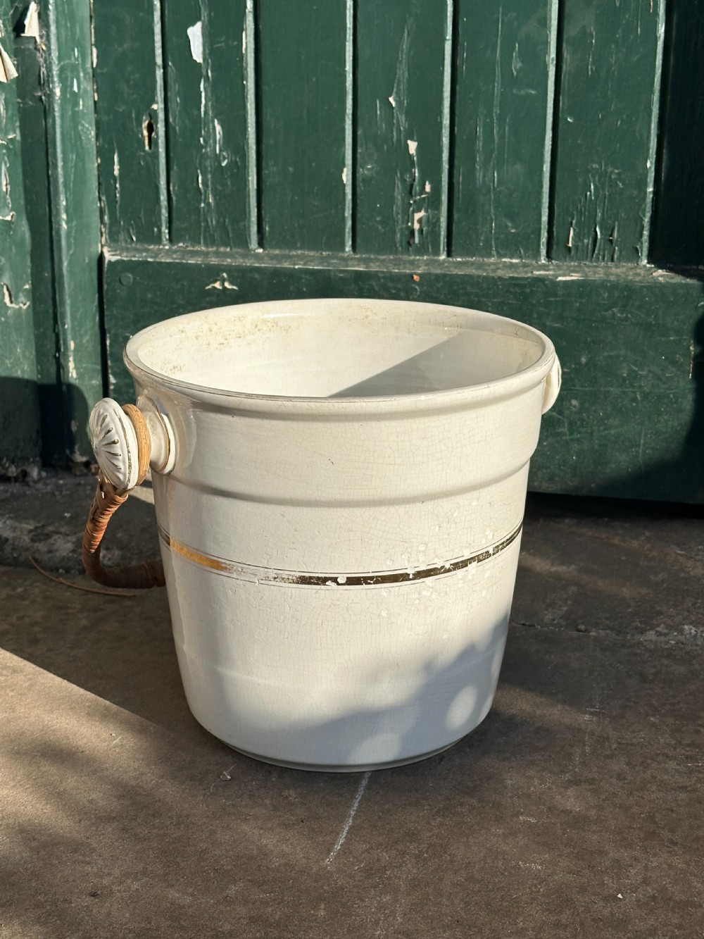 A cream-glazed ceramic bucket featuring a horizontal gilt line and a cane-wrapped overhead swing handle. View V