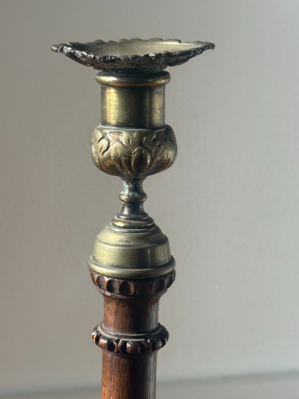 A pair of tall turned dark oak candlesticks with spiral-carved columns, circular bases, and brass sconces holding red tapered candles. View VI