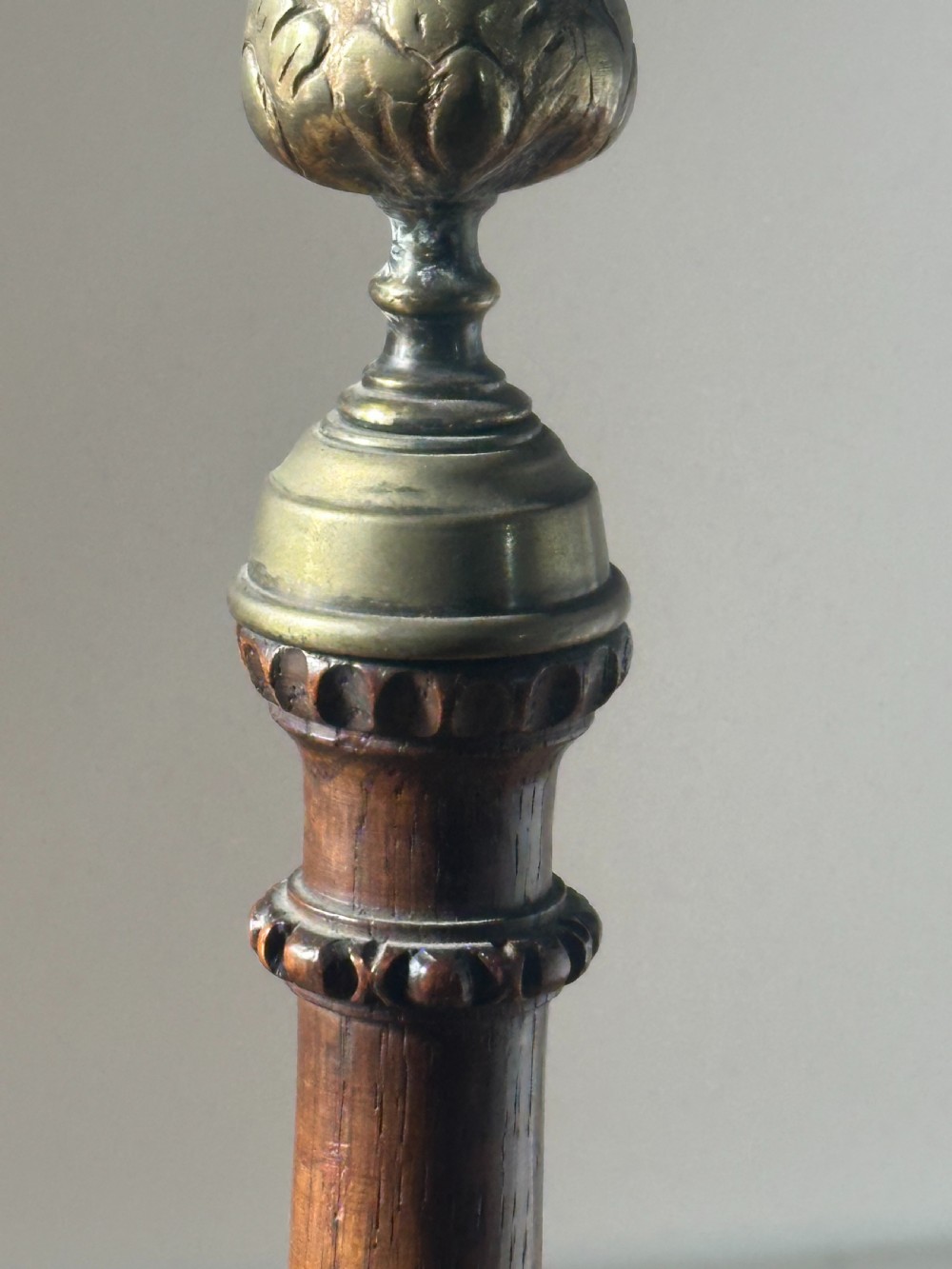 A pair of tall turned dark oak candlesticks with spiral-carved columns, circular bases, and brass sconces holding red tapered candles. View II