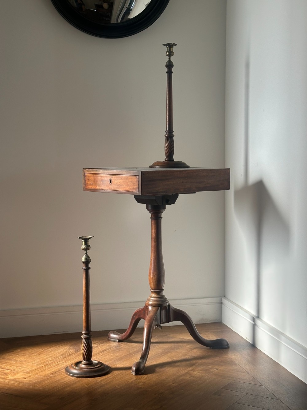A pair of tall turned dark oak candlesticks with spiral-carved columns, circular bases, and brass sconces holding red tapered candles. View VII