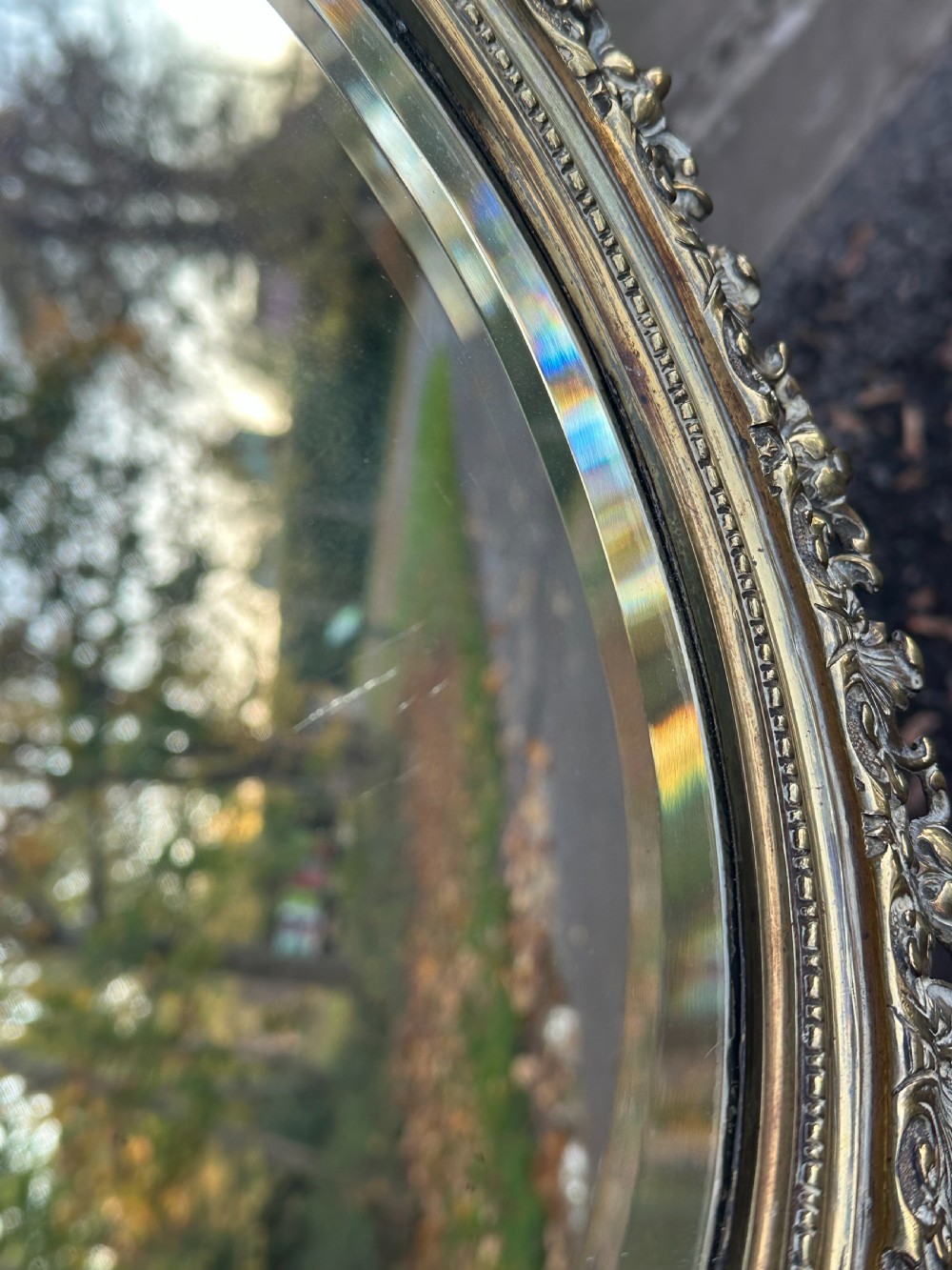 A circular Victorian cast brass wall mirror featuring a detailed crest with a mythological mask motif and a bevelled glass plate. View VI