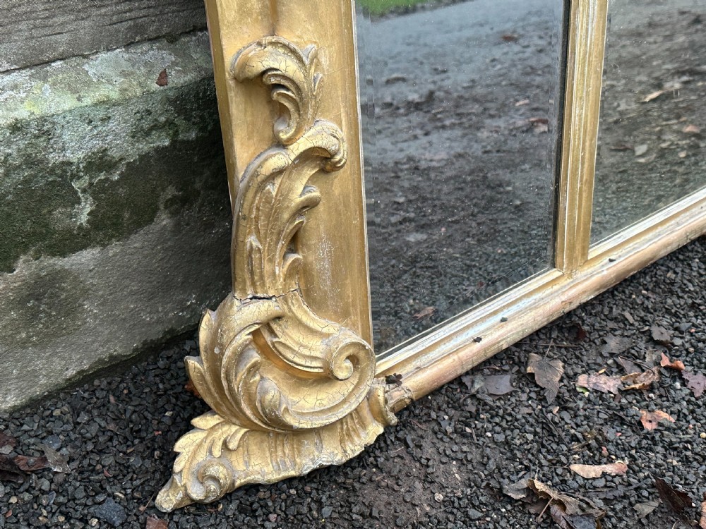 A wide 19th-century gilded gesso overmantel mirror featuring a three-panel glass design and ornate acanthus leaf cresting. View V