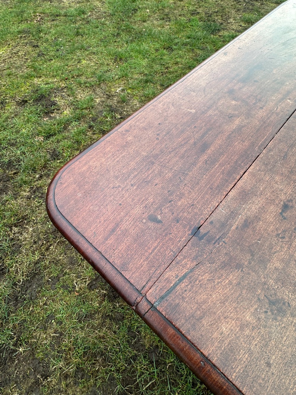 A Scottish Regency dark mahogany dining table featuring turned legs ending in brass castors and an integrated end drawer. View II