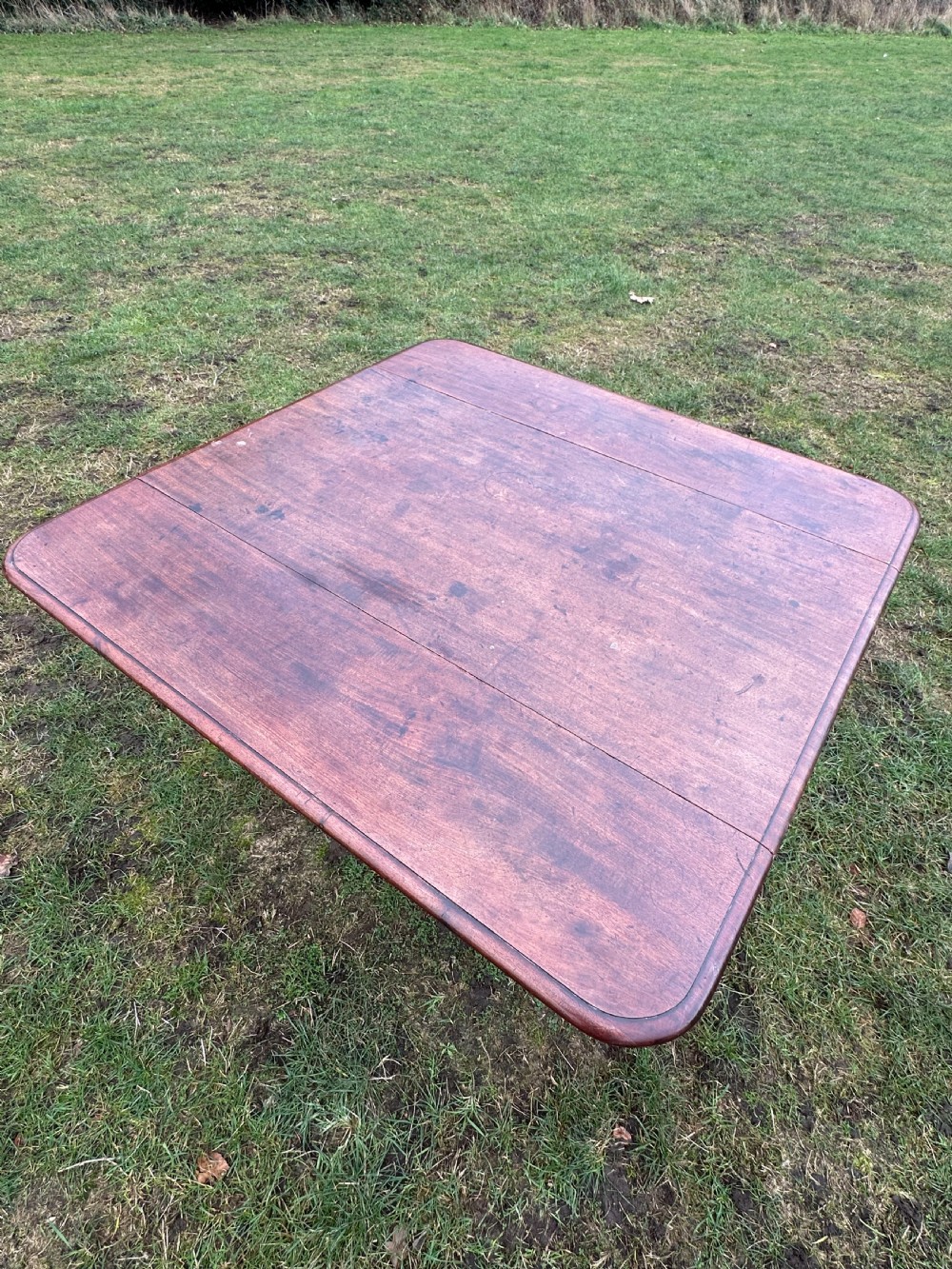 A Scottish Regency dark mahogany dining table featuring turned legs ending in brass castors and an integrated end drawer. View IV