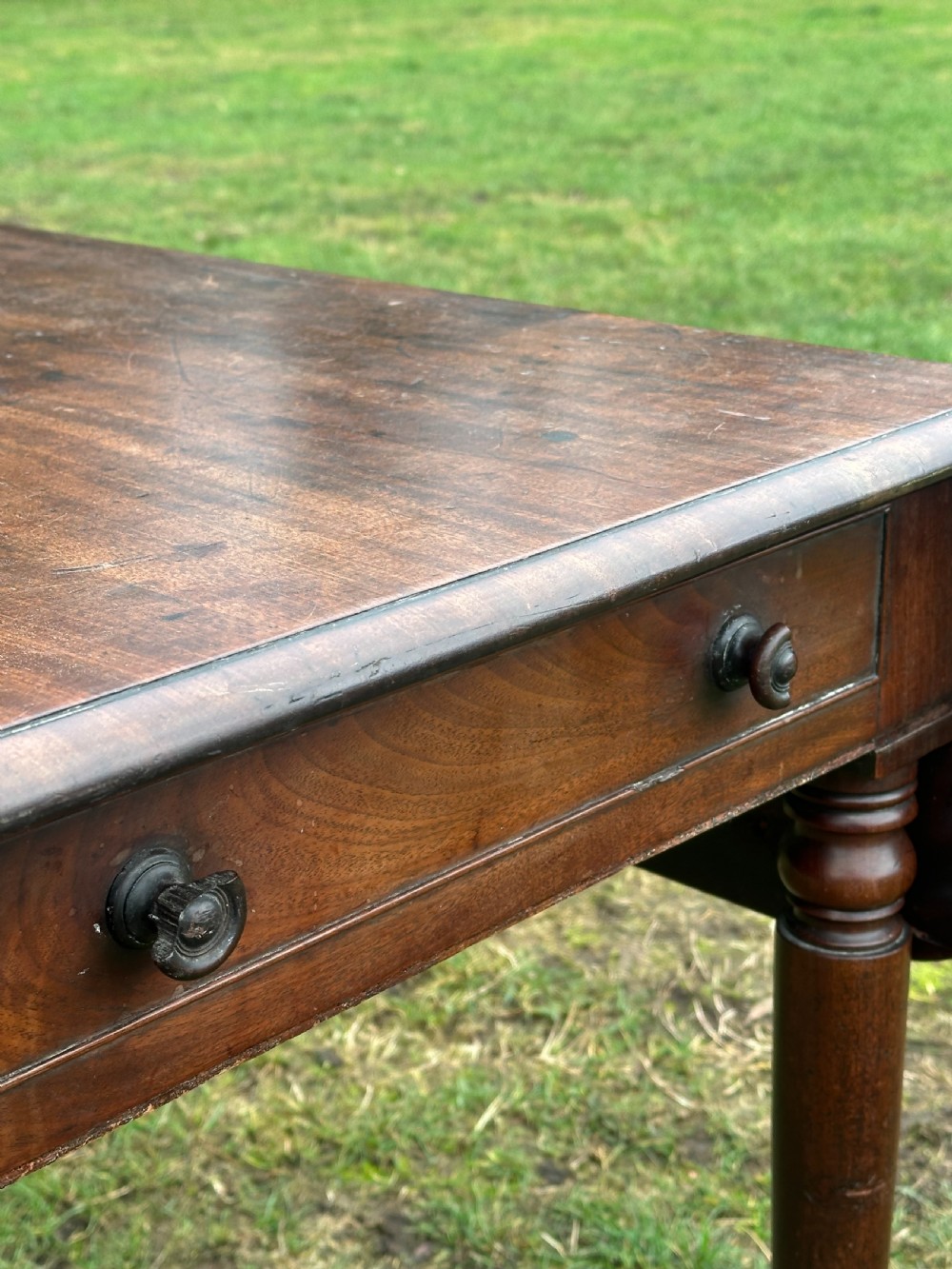 A Scottish Regency dark mahogany dining table featuring turned legs ending in brass castors and an integrated end drawer. View V