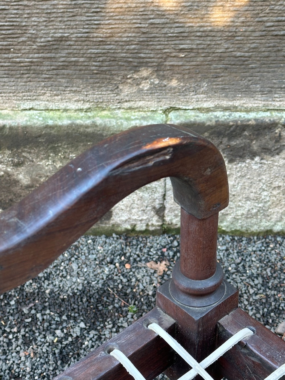 An early 19th-century South African stinkwood bench featuring a woven leather thong seat, curved armrests, and turned front legs. View XI