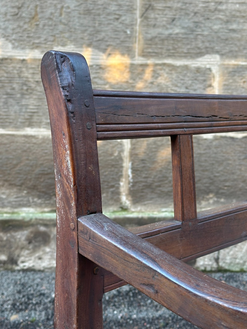 An early 19th-century South African stinkwood bench featuring a woven leather thong seat, curved armrests, and turned front legs. View VIII