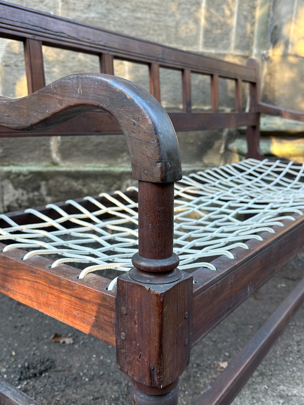 An early 19th-century South African stinkwood bench featuring a woven leather thong seat, curved armrests, and turned front legs. View IX