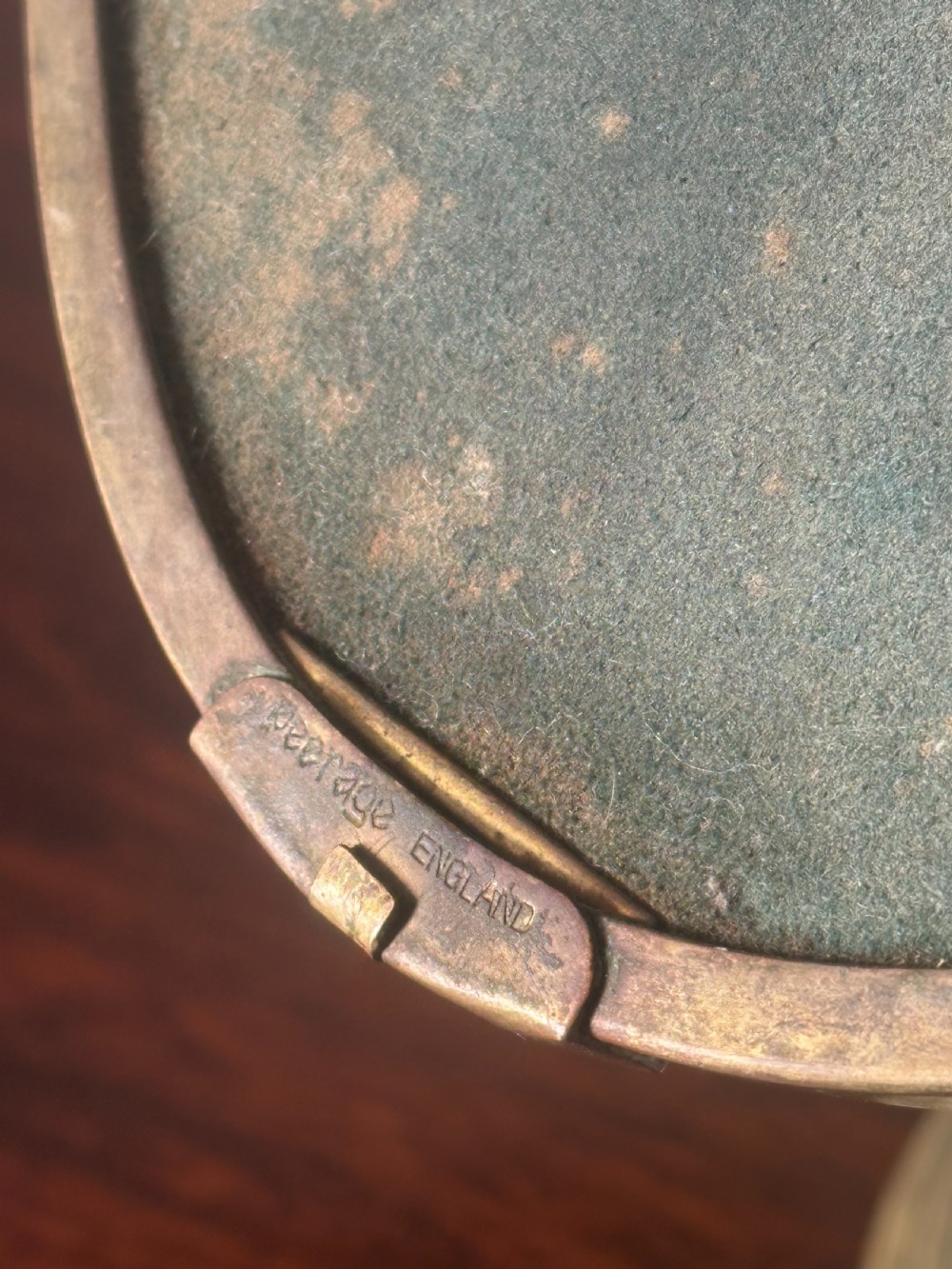 An oval brass shaving mirror on a matching stand sits atop a dark wooden surface. View VII