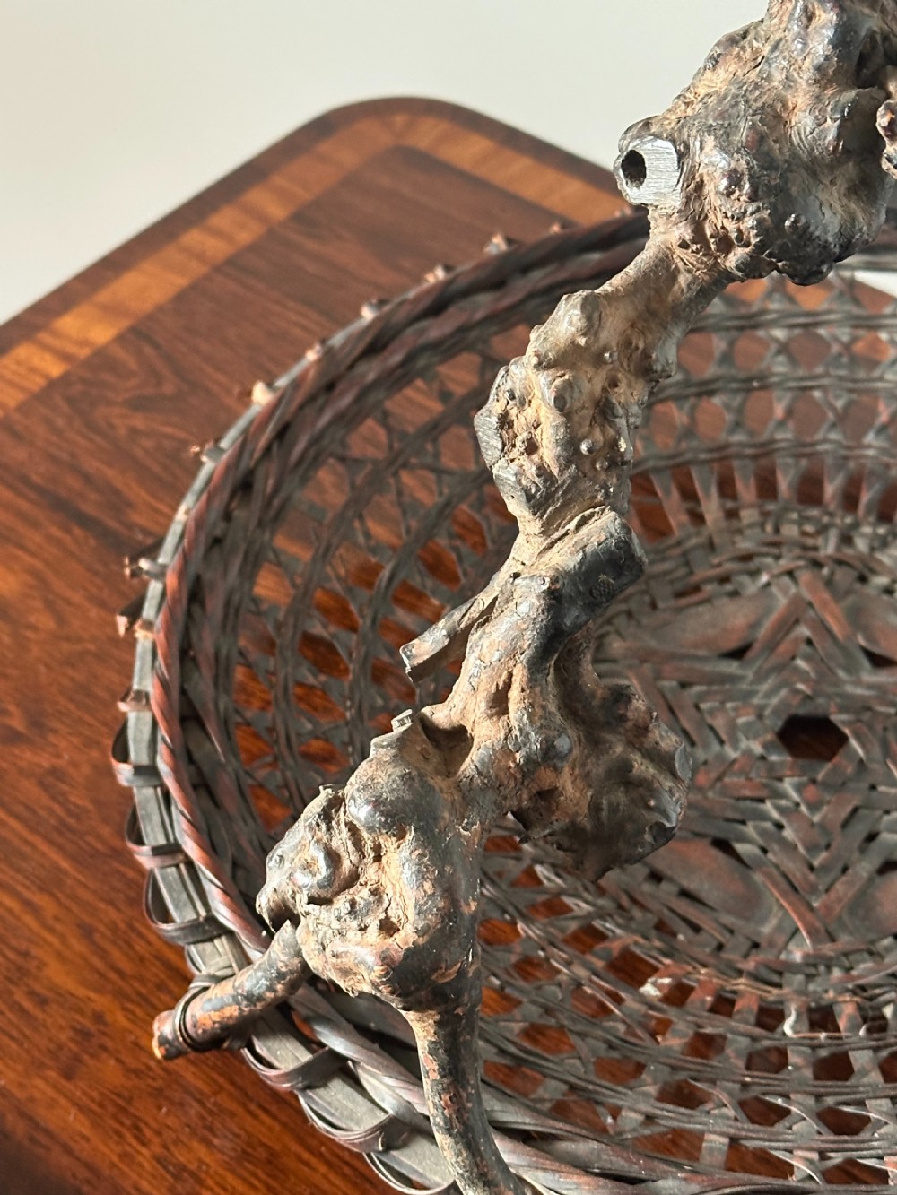 A shallow dark brown woven bamboo Ikebana flower basket featuring an organic gnarled natural rootwood overhead handle. View V