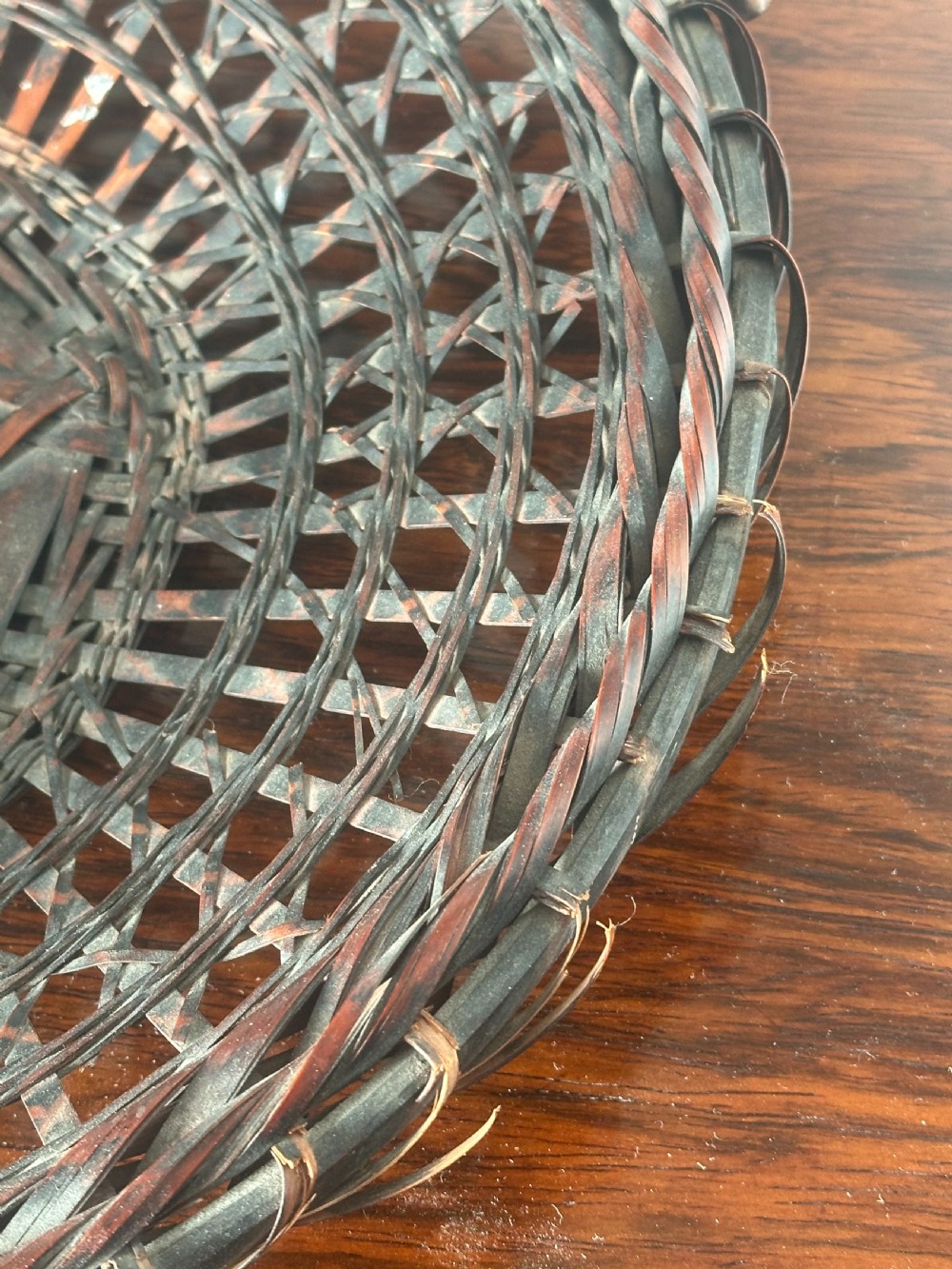 A shallow dark brown woven bamboo Ikebana flower basket featuring an organic gnarled natural rootwood overhead handle. View IX