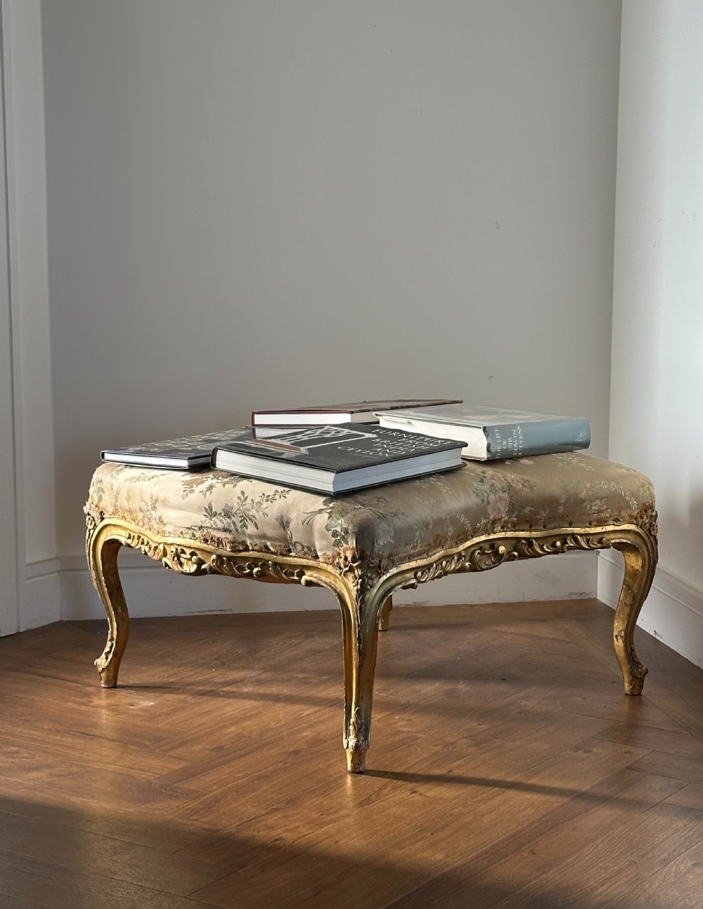 A 19th-century French giltwood centre stool featuring carved Rococo scrollwork, cabriole legs, and floral upholstered seating. View X