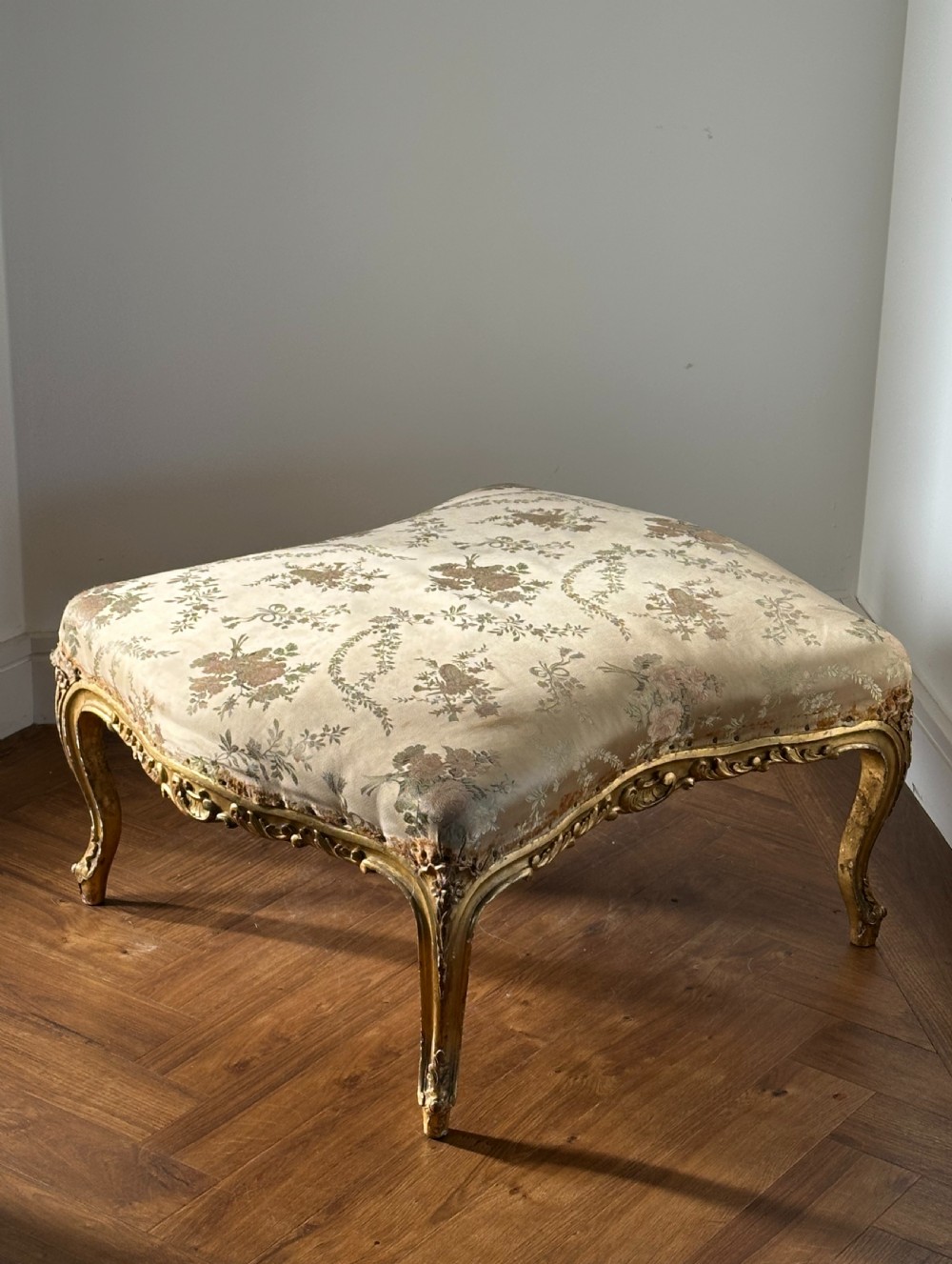 A 19th-century French giltwood centre stool featuring carved Rococo scrollwork, cabriole legs, and floral upholstered seating. View II