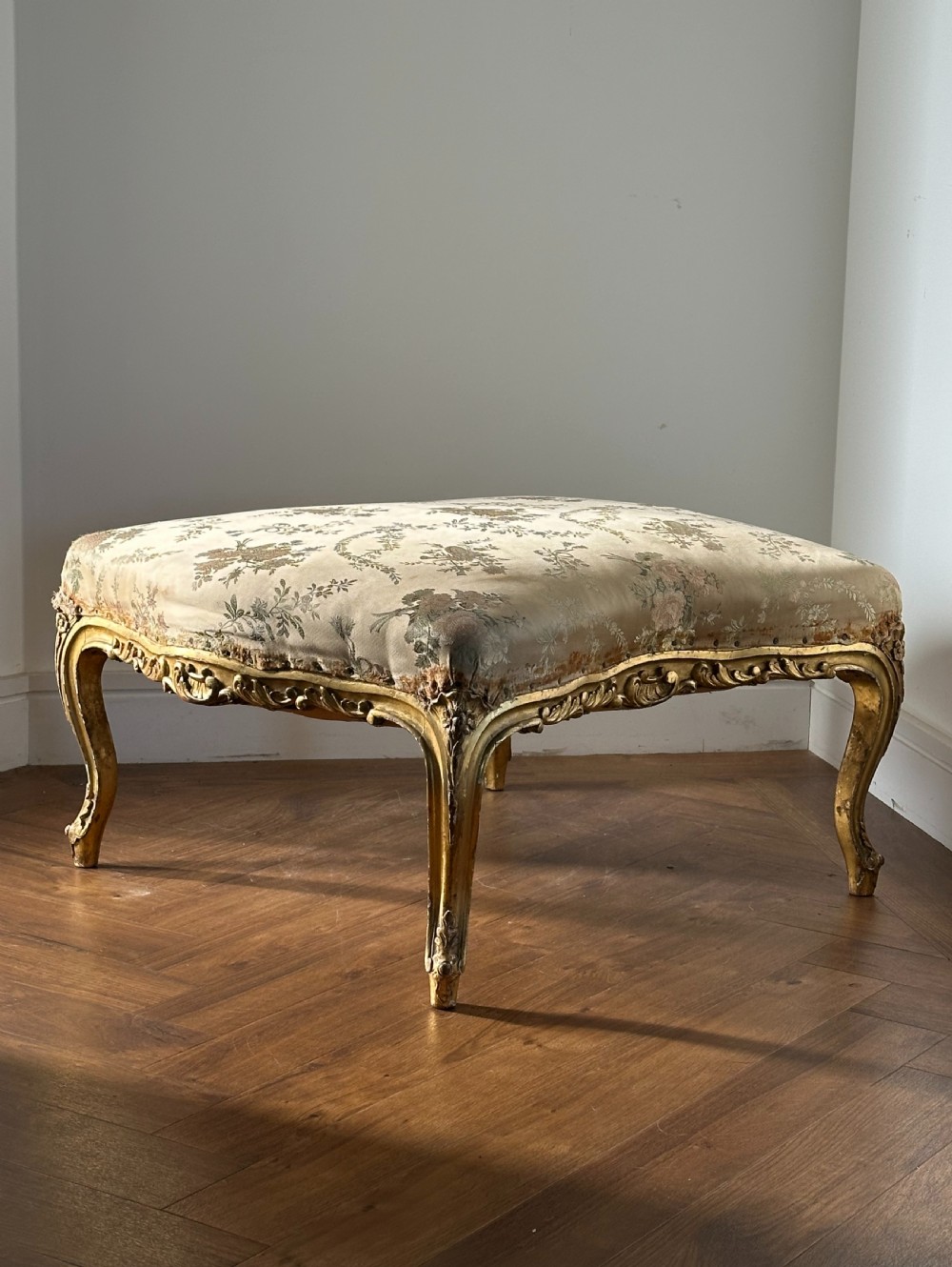 A 19th-century French giltwood centre stool featuring carved Rococo scrollwork, cabriole legs, and floral upholstered seating. View III